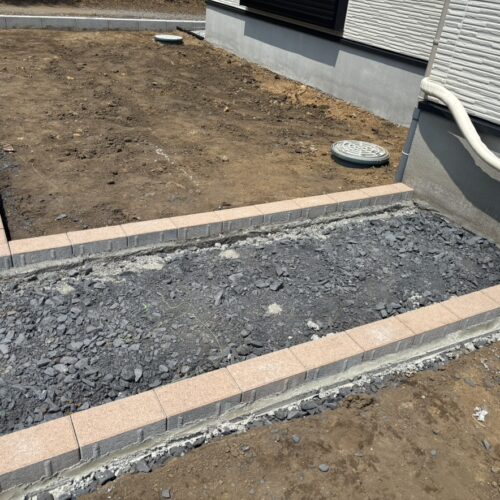 お庭のインターロッキングの見切りの敷設作業となります。