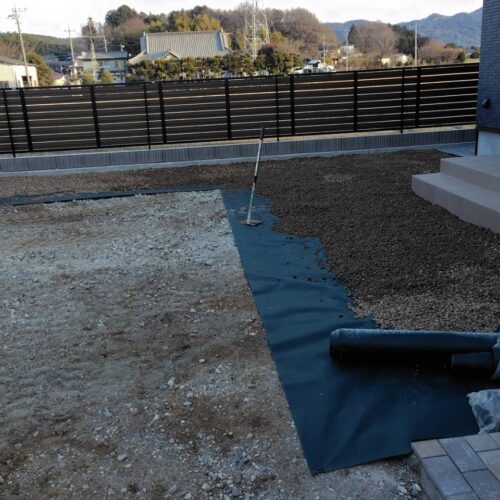 玄関前およびアプローチ横に防草シートを敷いて茶色の砕石チャートの敷き込み作業となります。