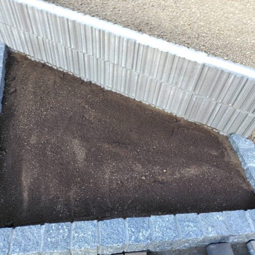 入り口グラニートの花壇部分への黒土入れ作業となります。