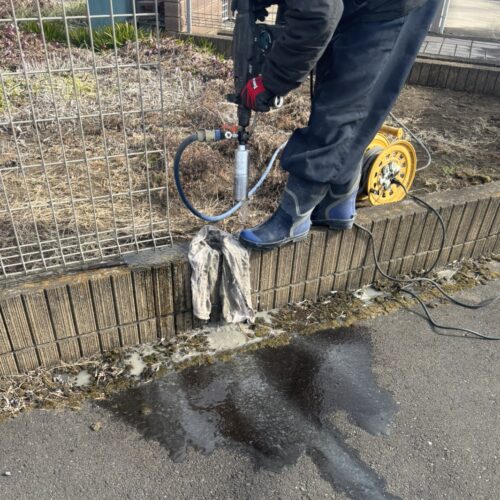 フェンス改修工事の既存のフェンスの柱を撤去した後に新設の柱を設置する為にコア穴明けの作業となります。